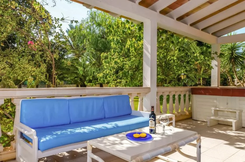 A covered outdoor seating area with a blue cushioned sofa and a low table.