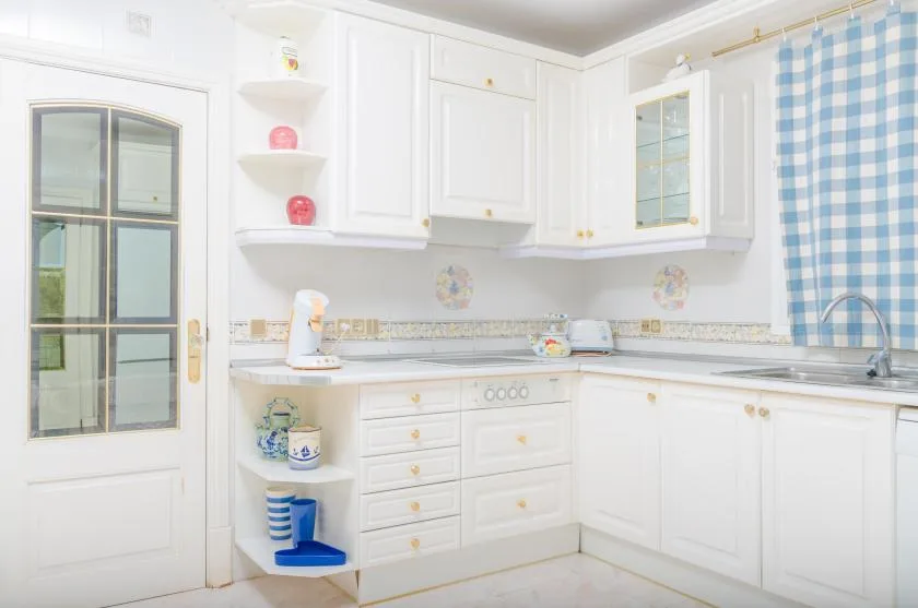 A bright white kitchen with cabinets, a countertop, and a sink.