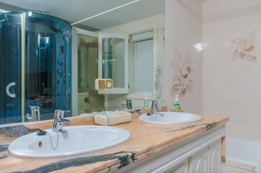 A bathroom vanity with two sinks, mirrors, and a blue shower.
