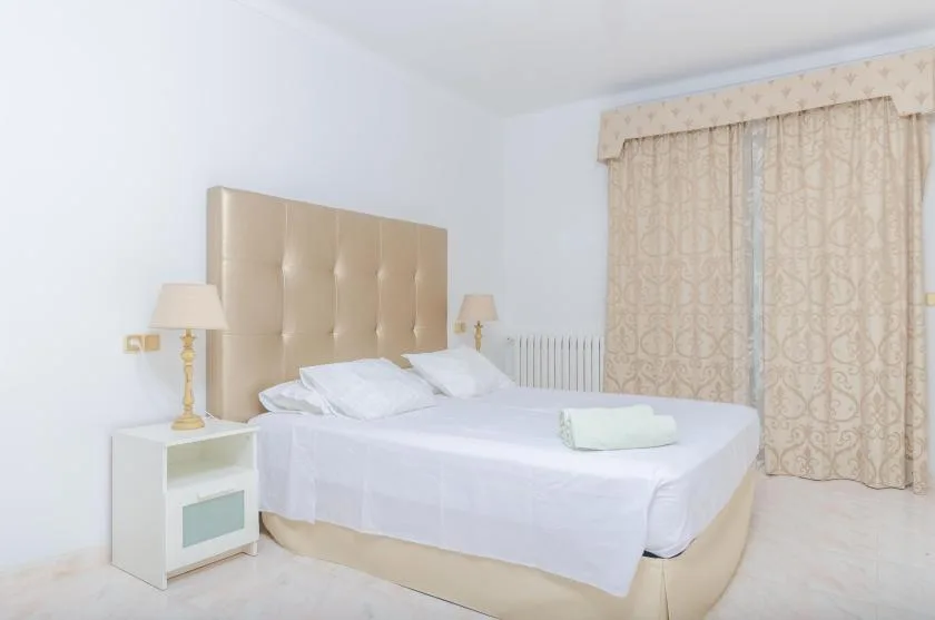 A bedroom with a neatly made bed and patterned curtains.