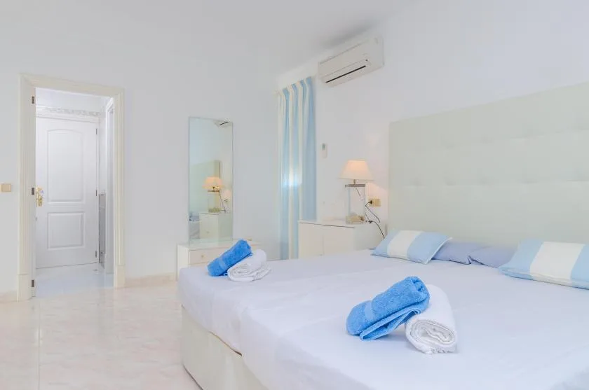 A bright bedroom with a neatly made bed and folded blue towels.