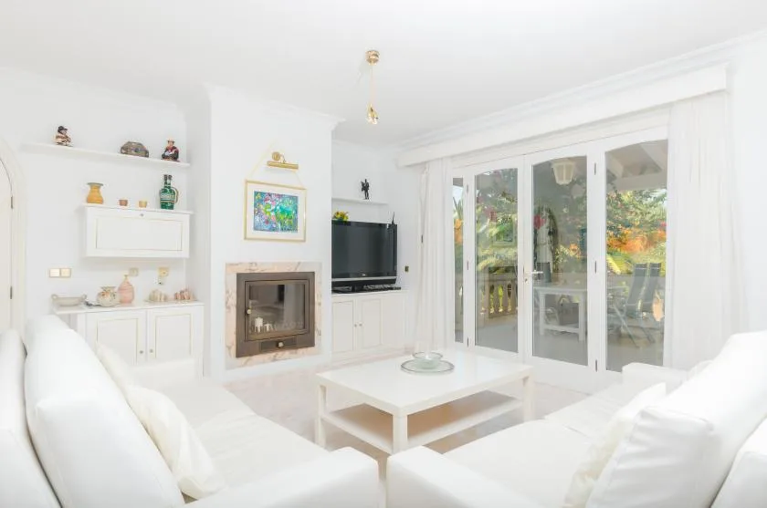 Bright living room with white seating, a coffee table, and glass doors opening to a patio.
