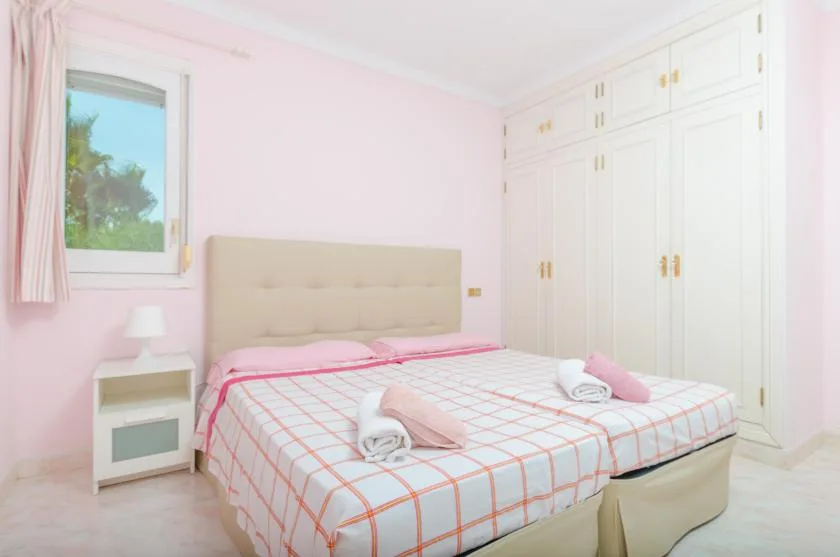A bedroom with a neatly made bed and built-in white wardrobes.