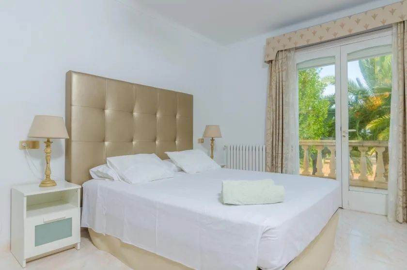 A bedroom with a neatly made bed and glass doors opening onto a balcony.