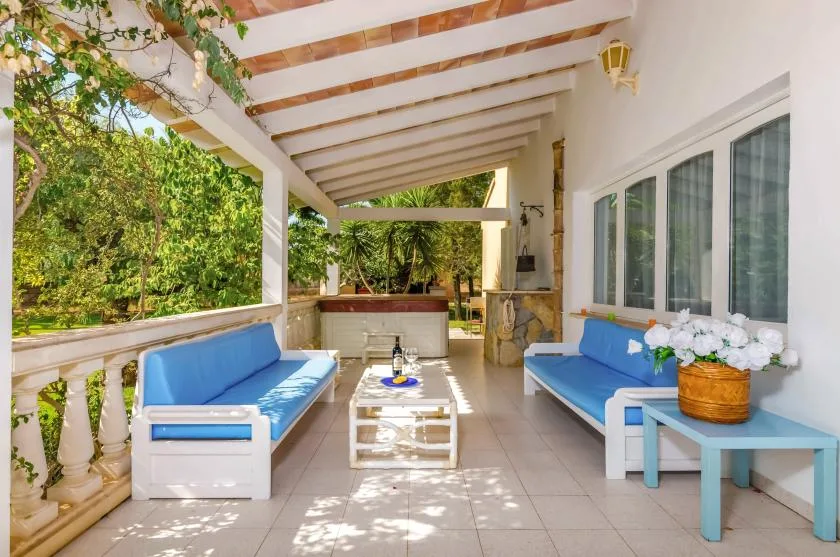 A covered outdoor lounge with blue seating and a low table.