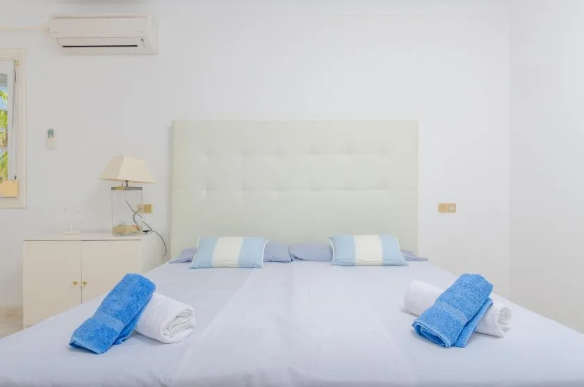 A bedroom with a neatly made bed and folded blue towels.