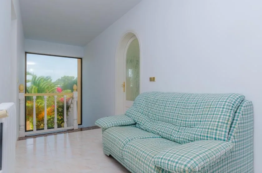 A bright sitting room with a checked sofa beside a glass balcony door.