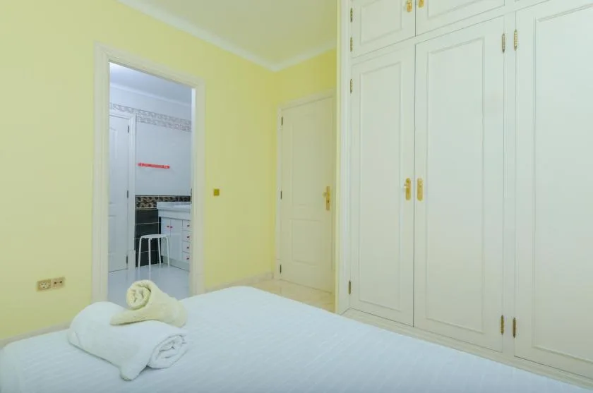 A bedroom with a white bed and built-in wardrobes.