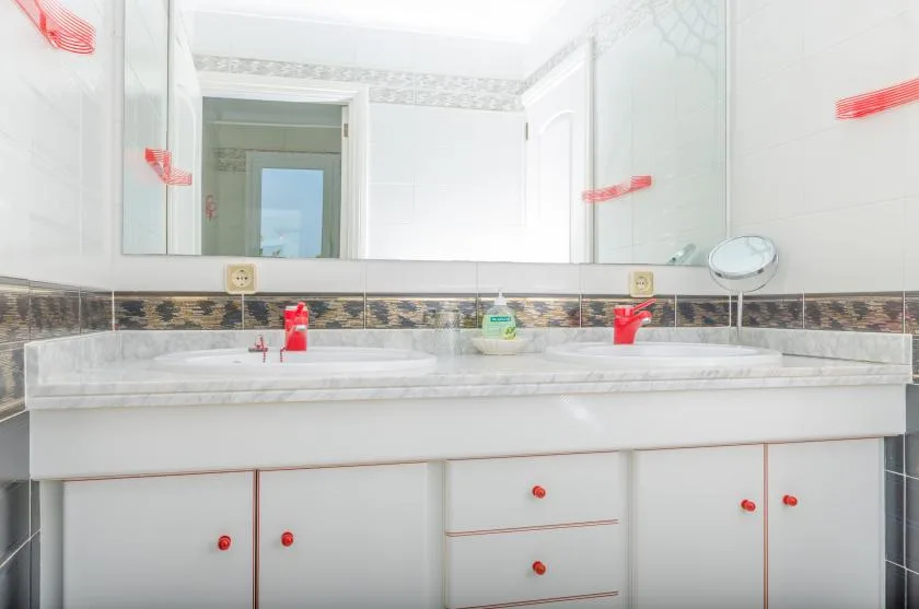 A bright bathroom vanity with a wide mirror and two sinks.