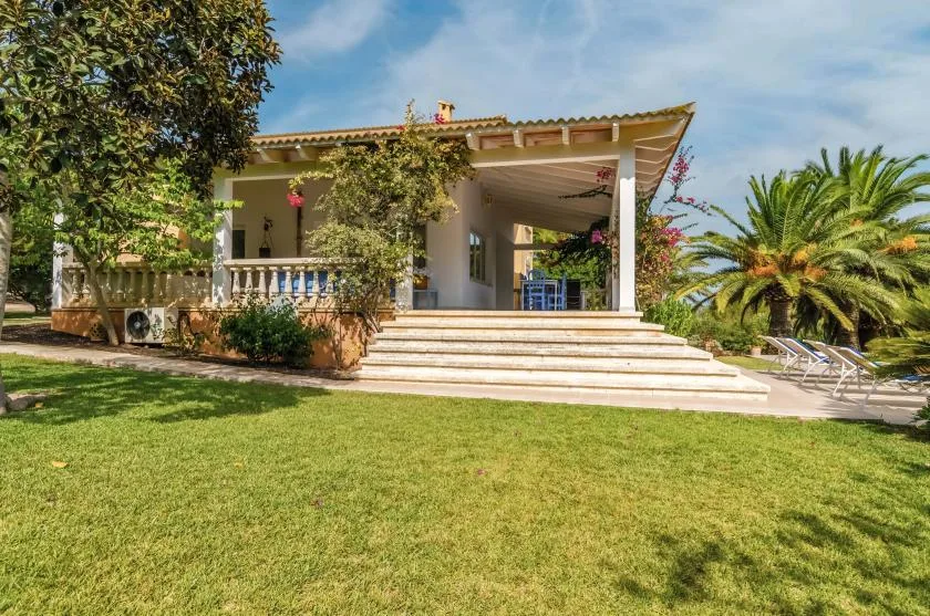 A covered patio opens onto a lawn, with steps leading up to the seating area.