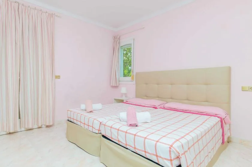 A bedroom with a double bed, pale bedding, and curtains.