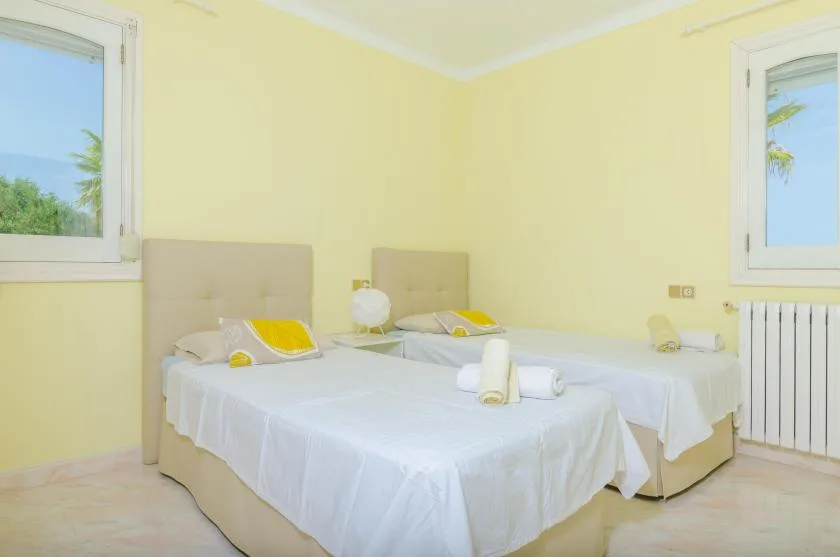 A bedroom with two beds, white bedding, and yellow walls.