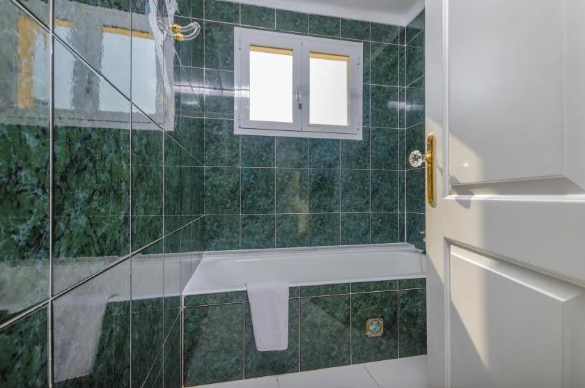 A tiled bathroom with a bathtub beneath a small window.