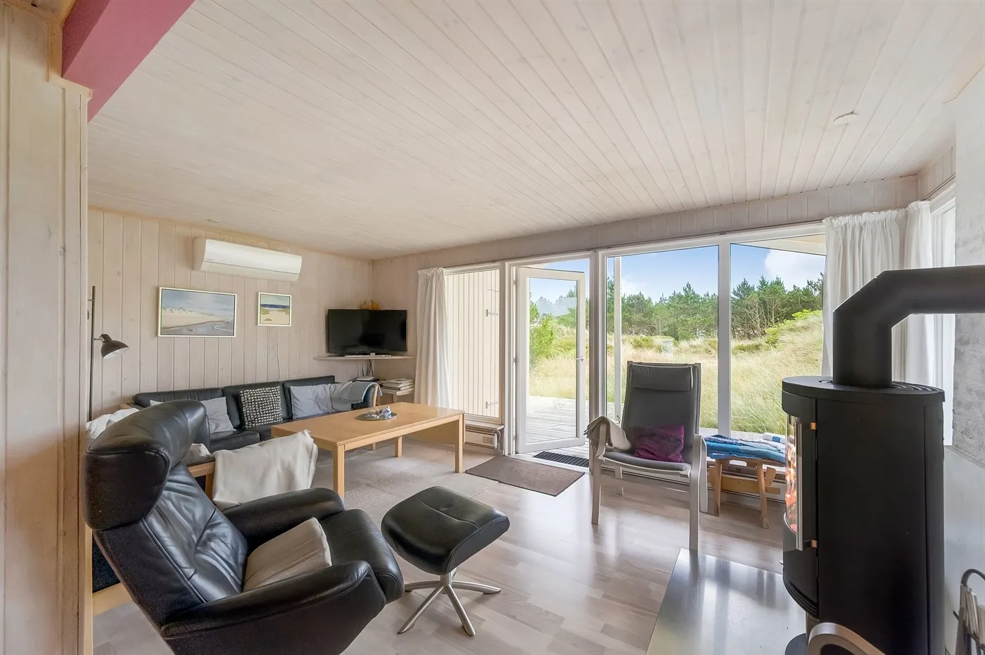 A bright living room with seating facing large windows and a wood-burning stove.