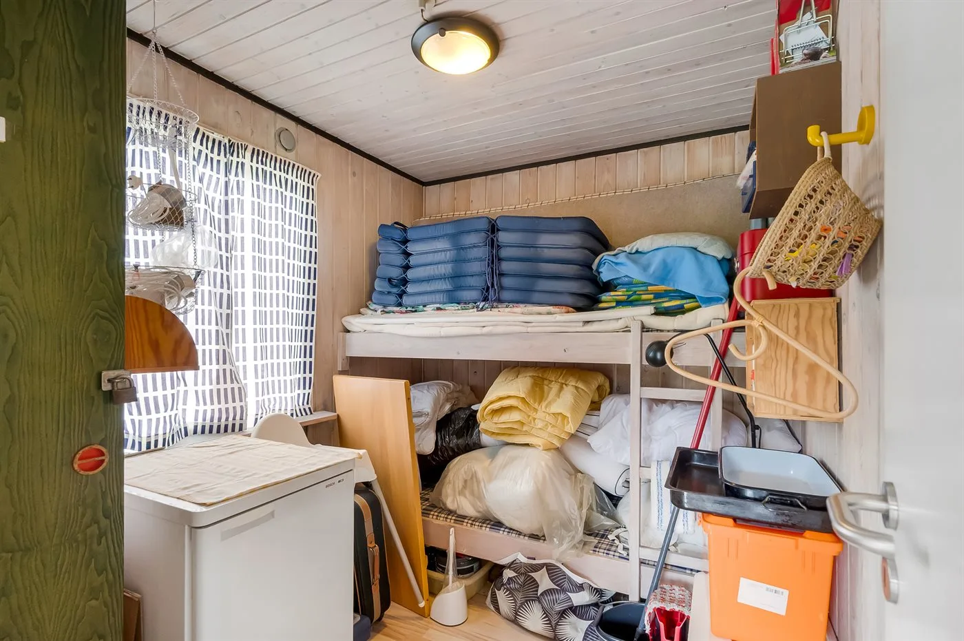 A compact storage room with folded bedding stacked on shelves.
