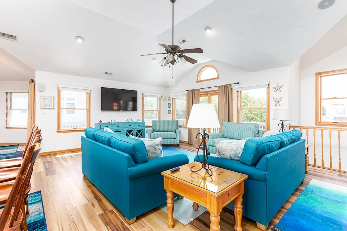 A bright living room with teal seating arranged around a wooden coffee table.