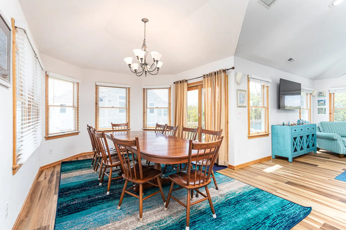 A dining area with a wooden table and chairs on a blue rug.
