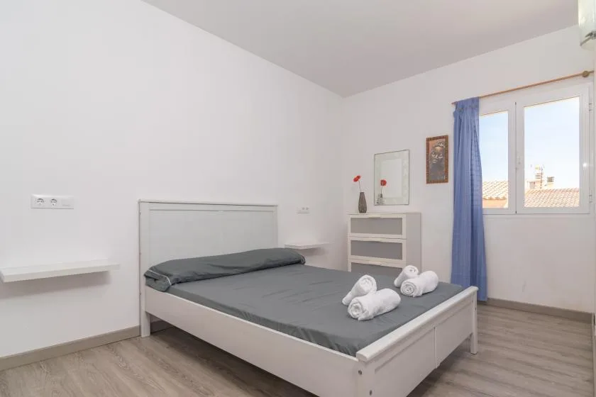 A bright bedroom with a gray bed and a window framed by blue curtains.
