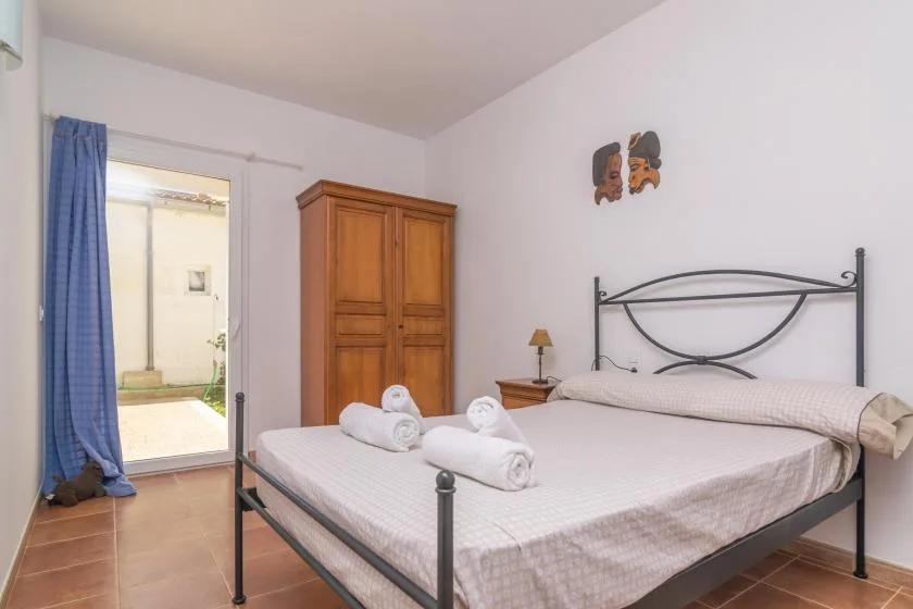 A bedroom with a double bed, a wooden wardrobe, and a blue curtain beside the window.