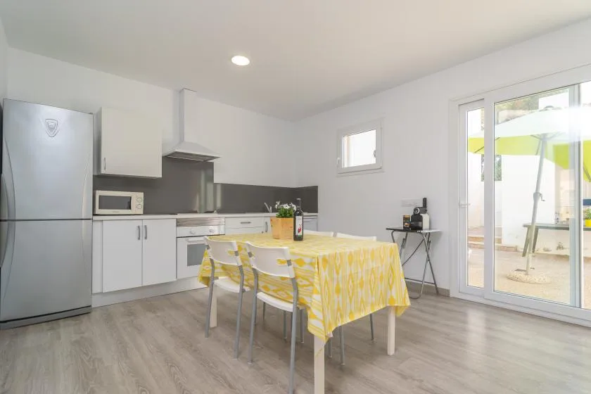 A bright kitchen and dining area with a yellow-covered table beside sliding glass doors.