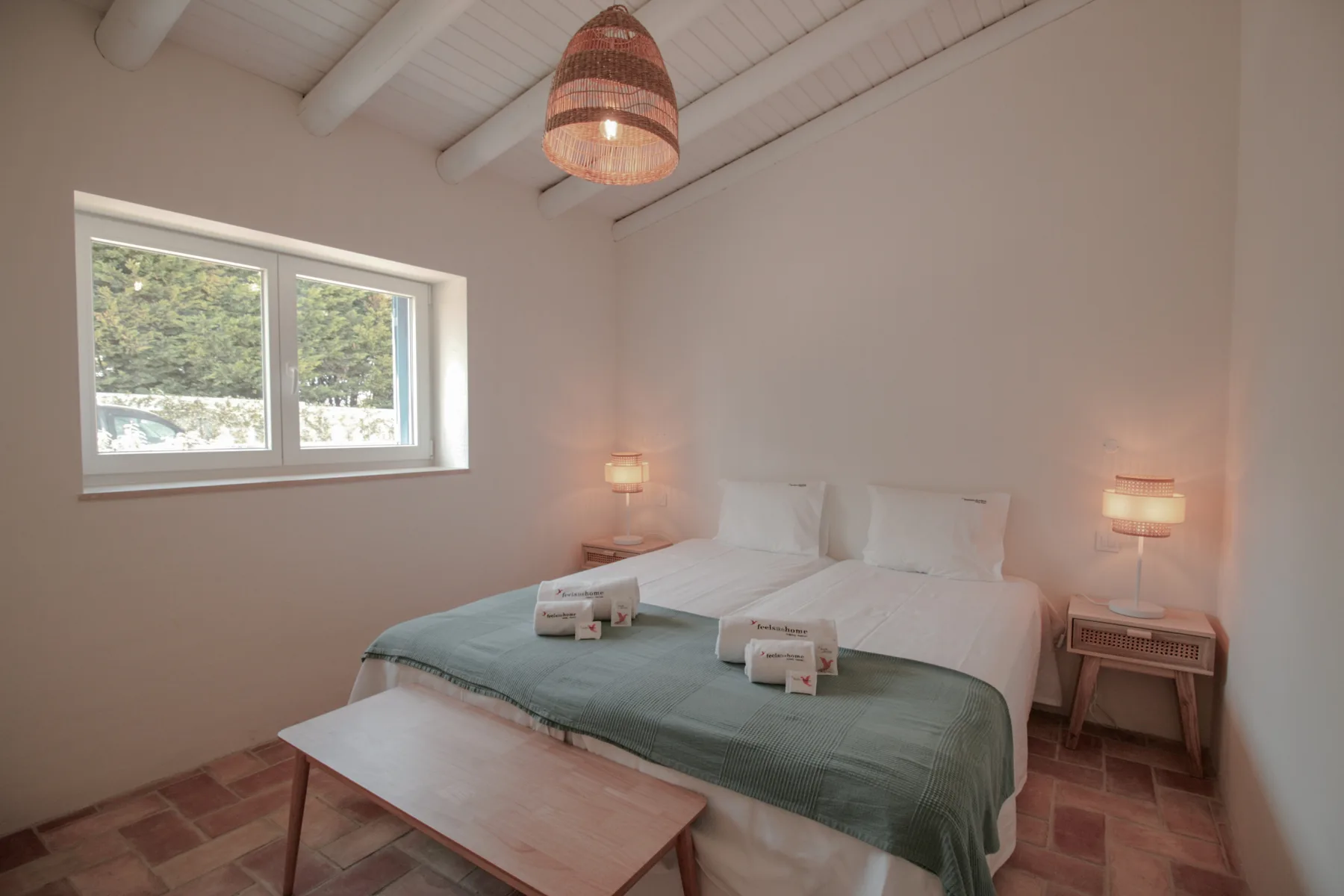 Un dormitorio con una cama, lámparas de noche y una ventana con vistas a la vegetación.