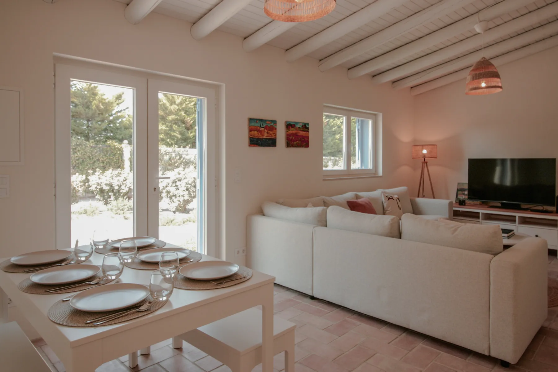 Una luminosa sala de estar y comedor con asientos, una mesa y grandes ventanas.