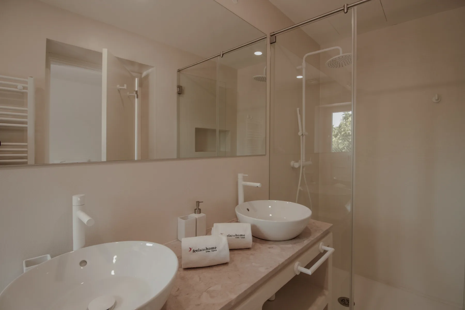 Un baño con un mueble largo, dos lavabos y una ducha de vidrio.