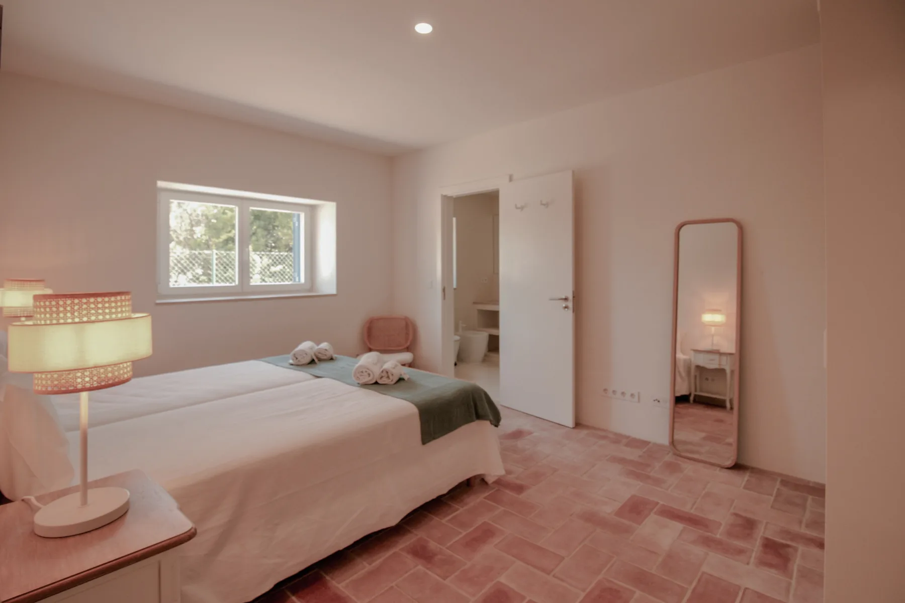 Un dormitorio con una cama, una ventana y un espejo de pie.