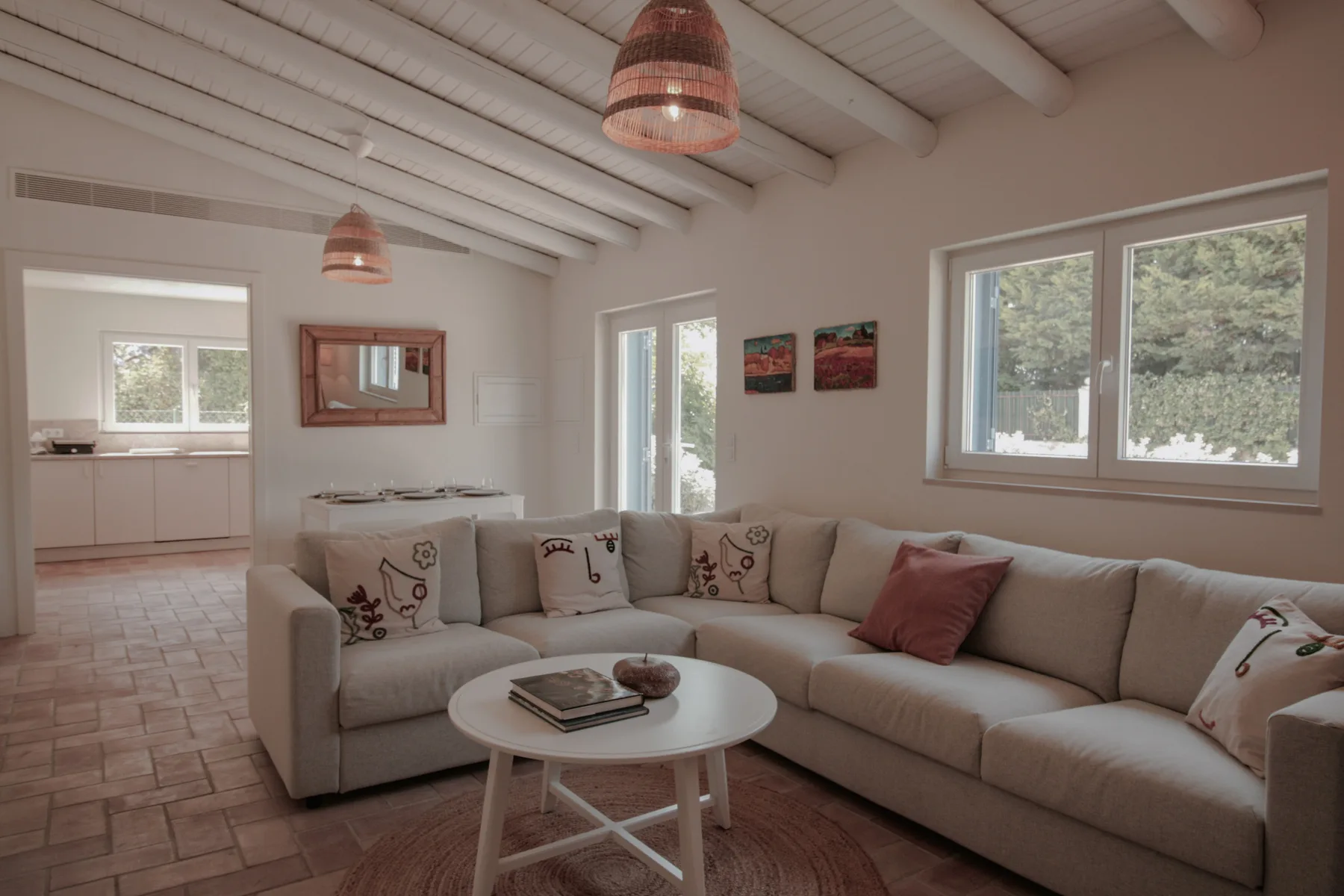 Una sala de estar con una zona de asientos y ventanas con vistas a la vegetación.