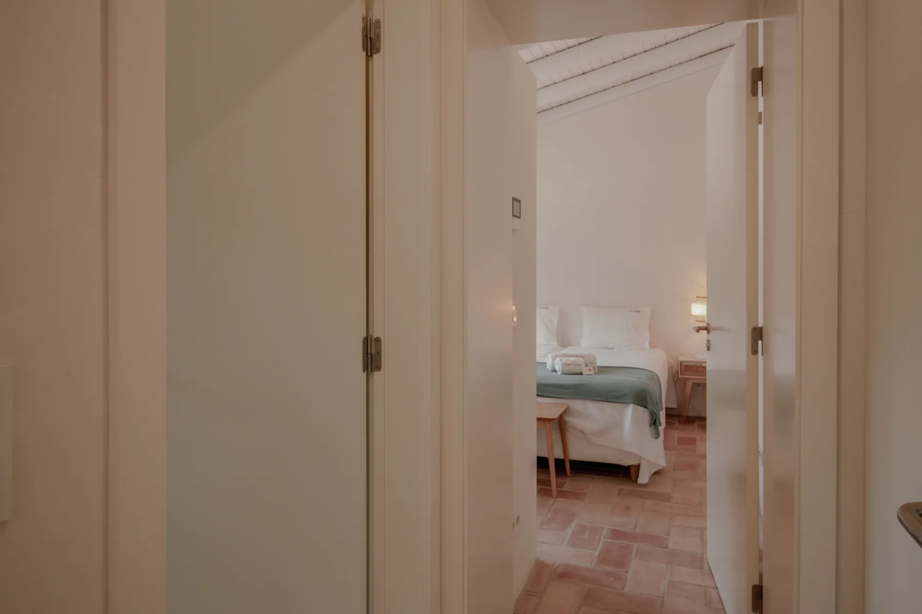 Un dormitorio con una cama se ve a través de una puerta abierta.