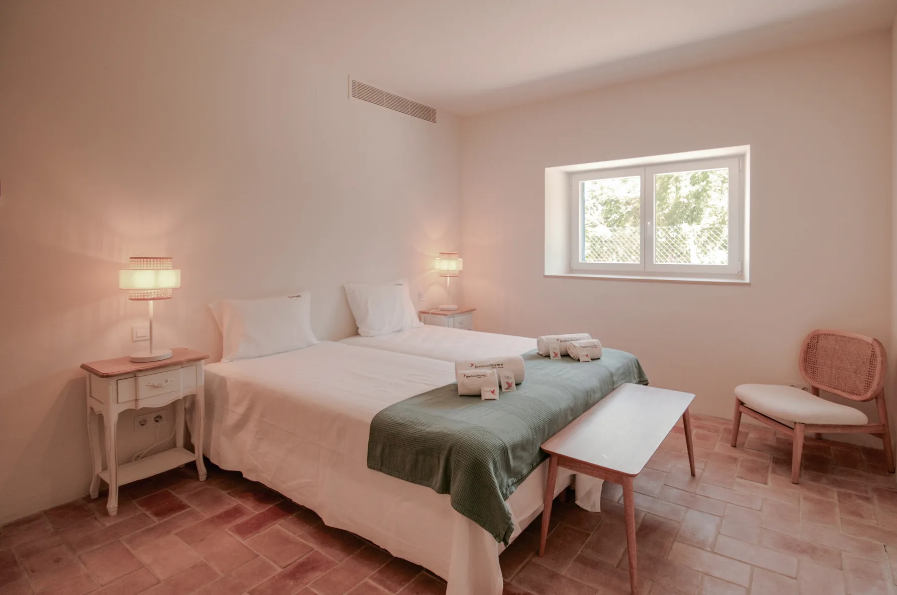 Un dormitorio con una cama cubierta con una manta verde y una ventana.