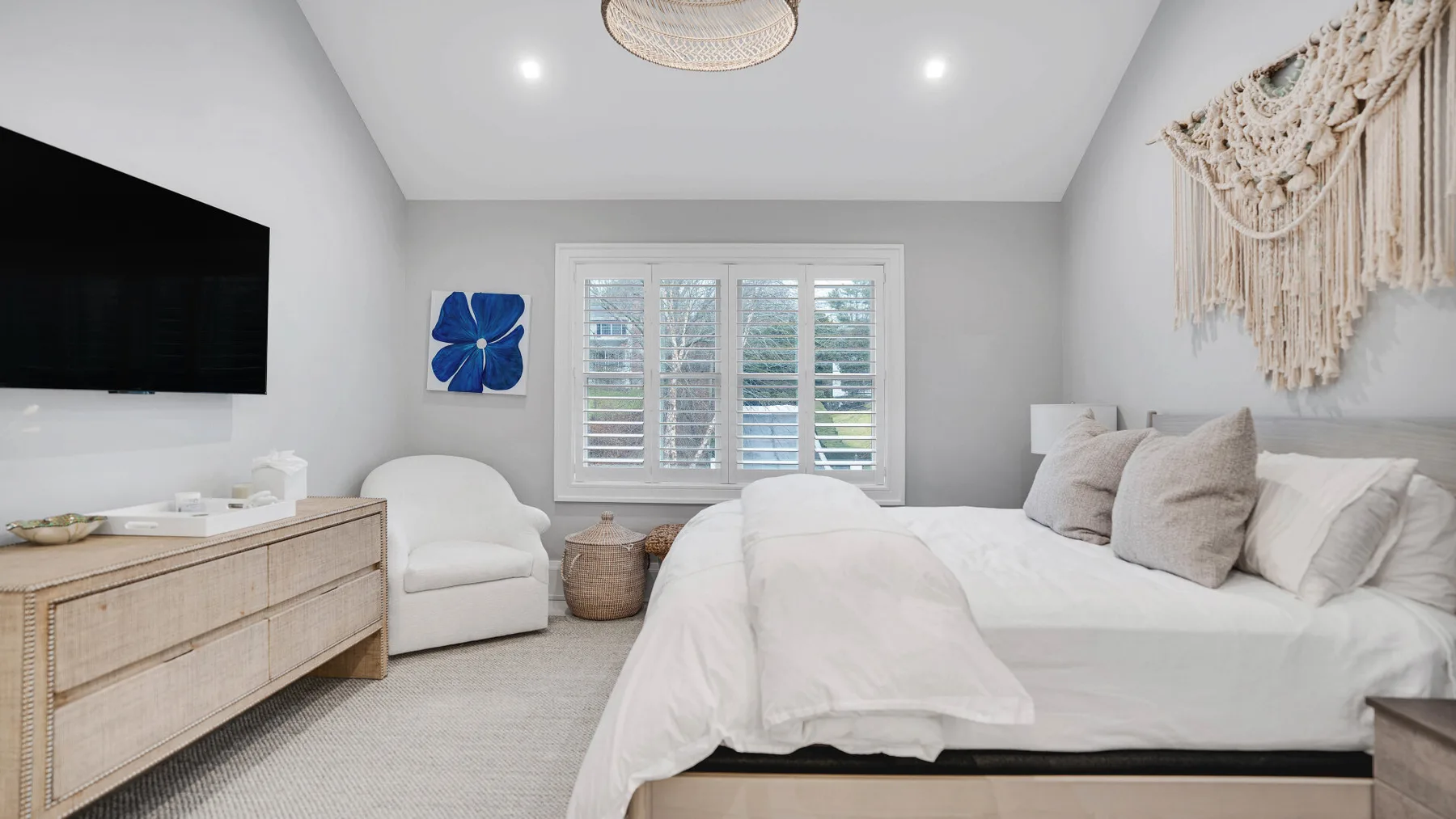 Un dormitorio luminoso con una cama, una ventana y un televisor.
