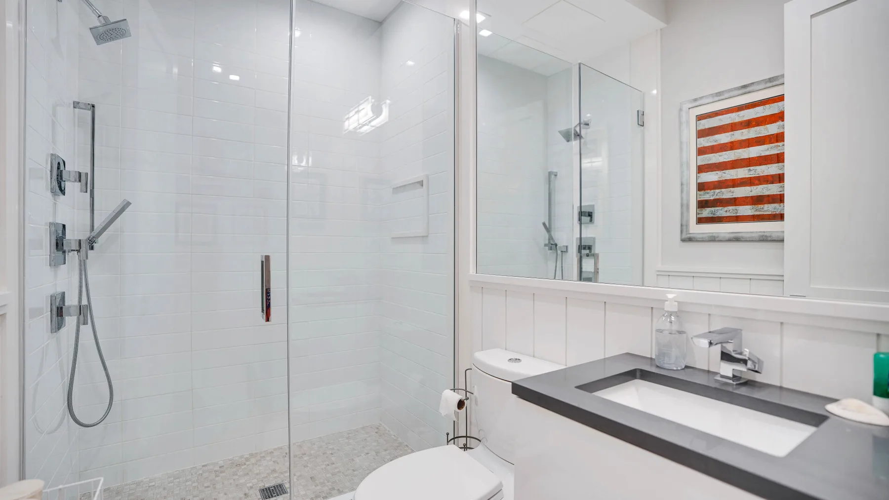 Un baño luminoso con ducha de vidrio y lavabo con mueble.