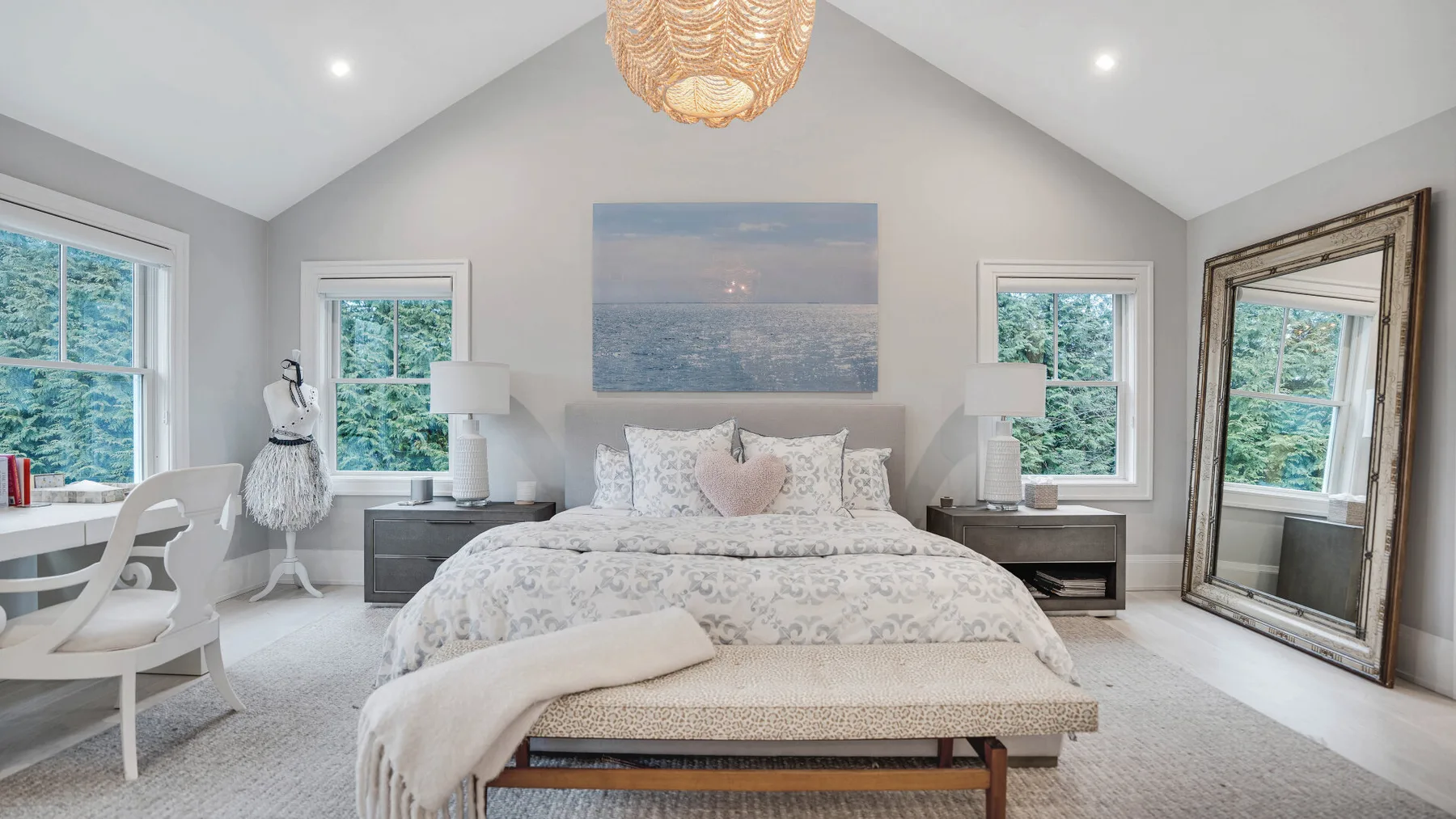 Un dormitorio luminoso con una cama centrada bajo una pintura marina.
