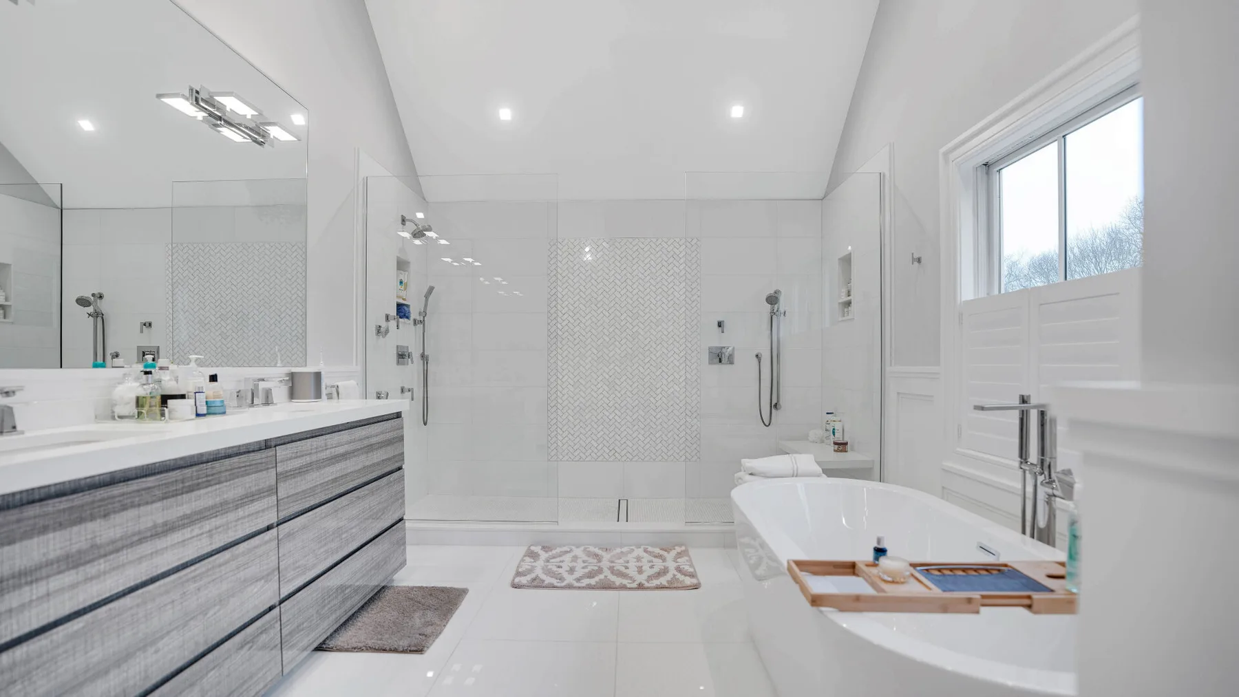 Un baño luminoso con un amplio tocador y una bañera junto a la ventana.