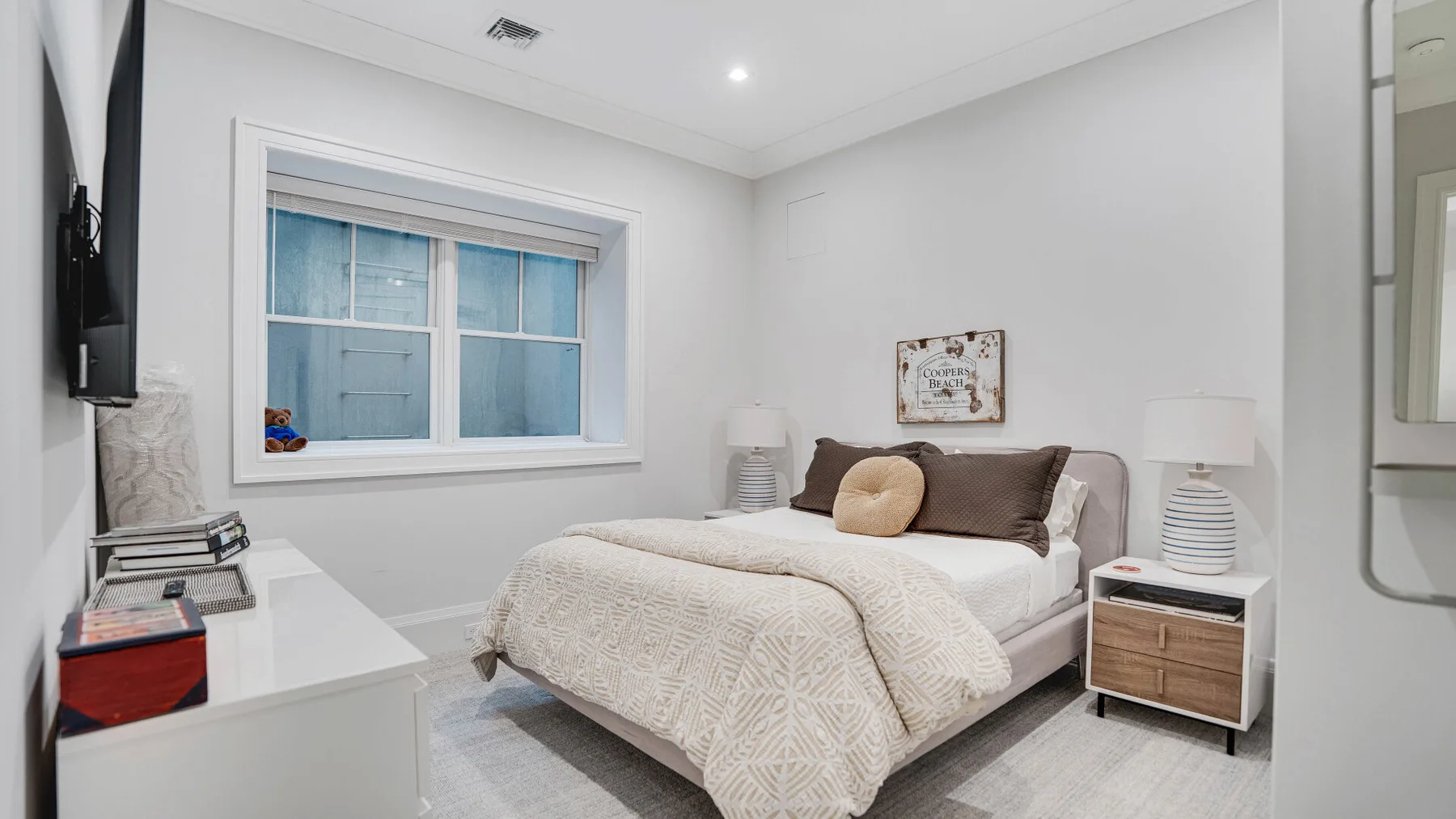 Un dormitorio luminoso con una cama, mesitas de noche y una ventana grande.