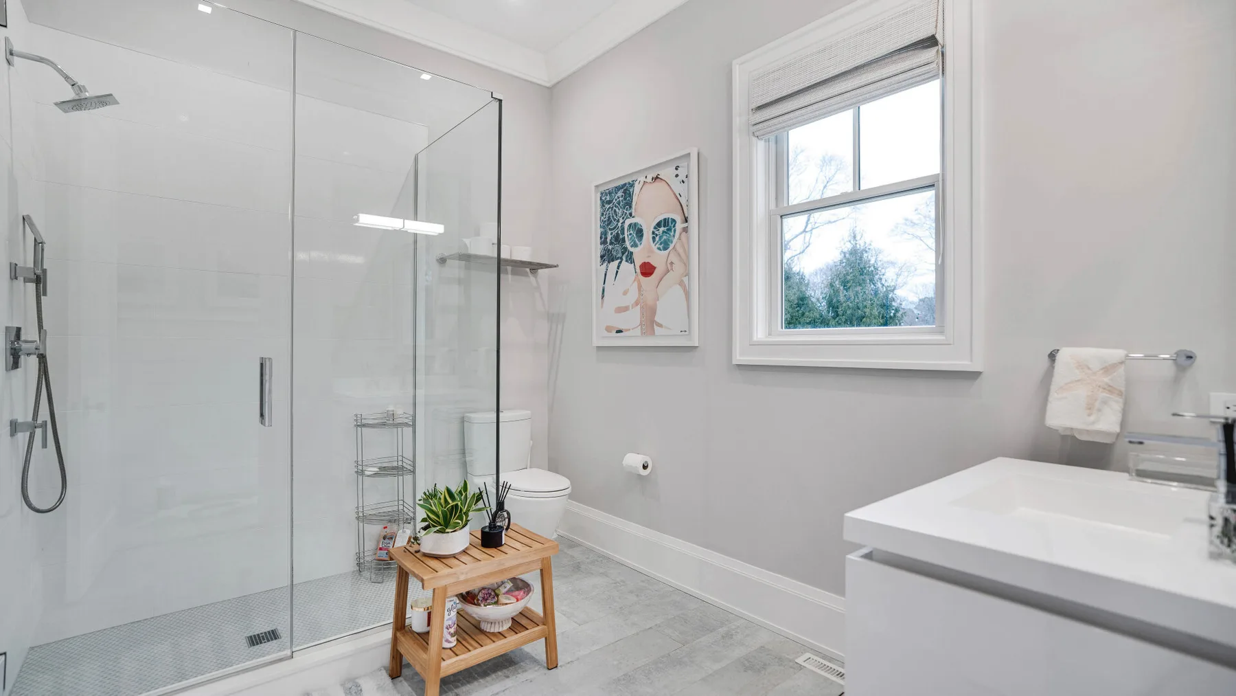 Un baño luminoso con ducha de vidrio, ventana y lavabo.