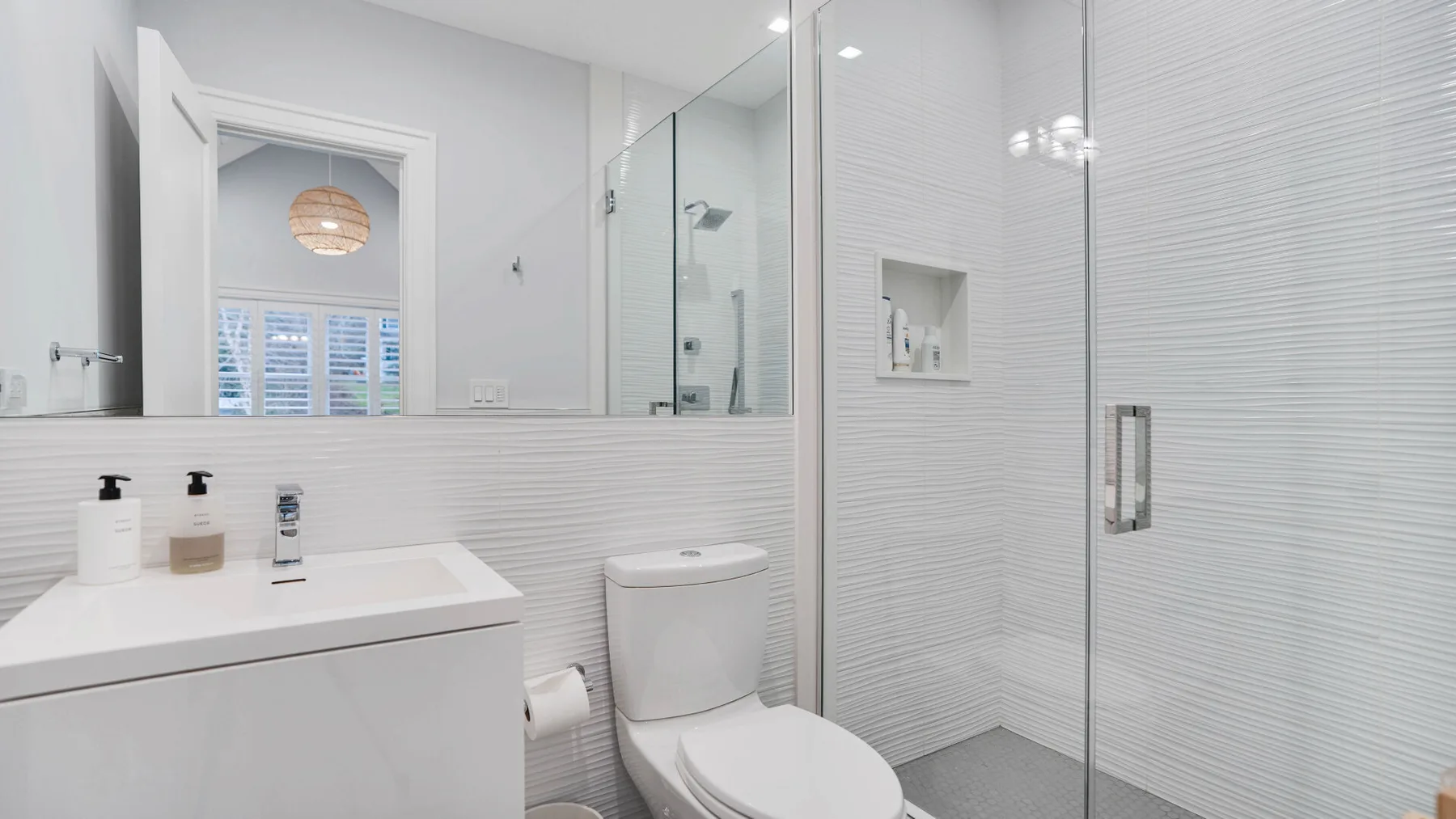 Un baño luminoso con lavabo, inodoro y ducha de vidrio.