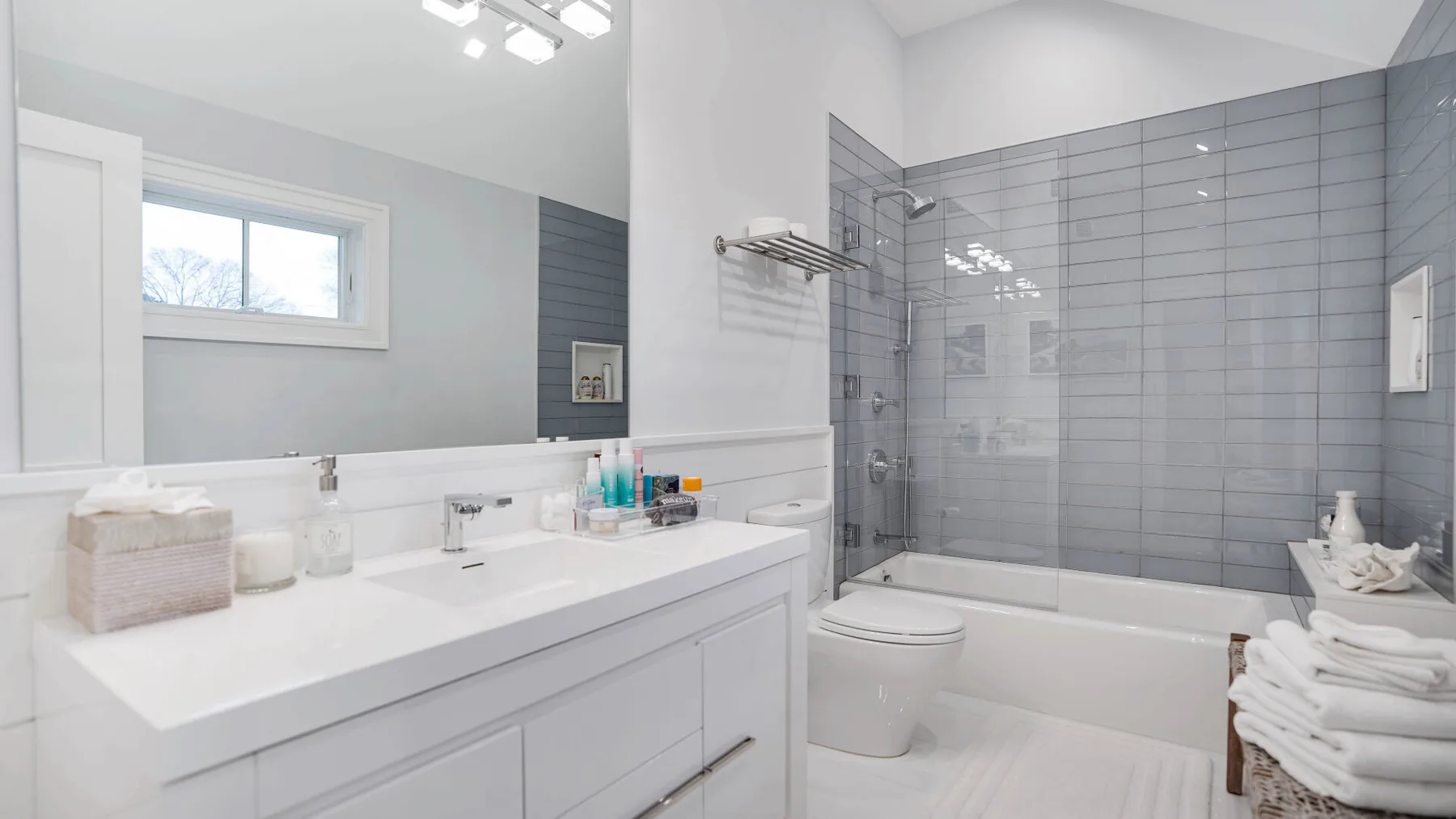 Un baño luminoso con bañera, mampara de vidrio y lavabo blanco.