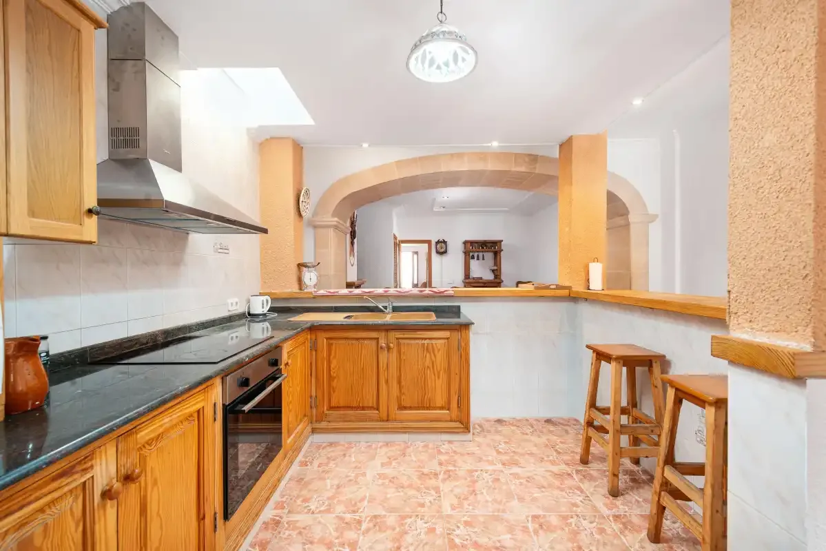 A kitchen with wooden cabinets, dark countertops, and a central island.