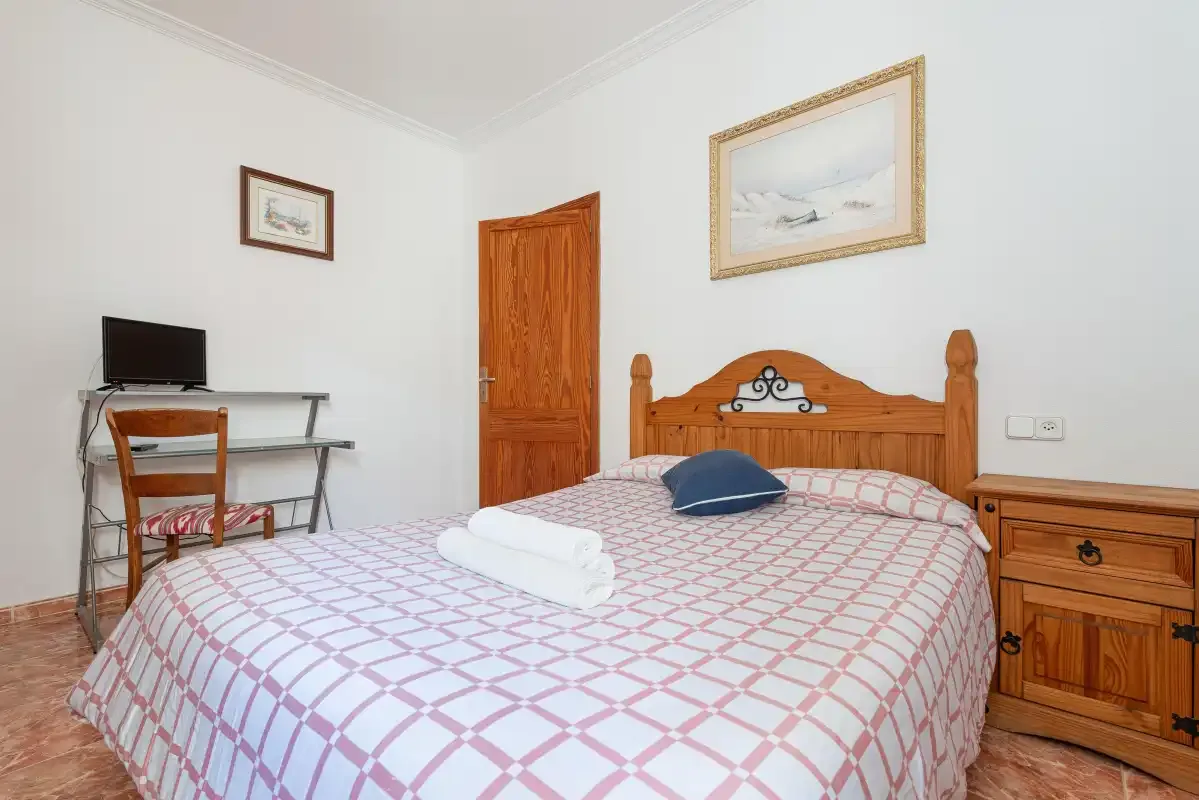 A bedroom with a wooden bed and a small desk.