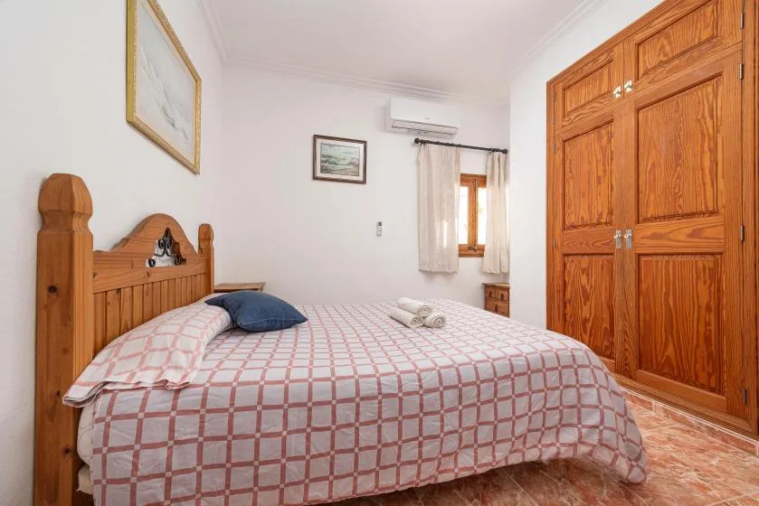 A bedroom with a wooden bed, patterned bedding, and a large wooden wardrobe.