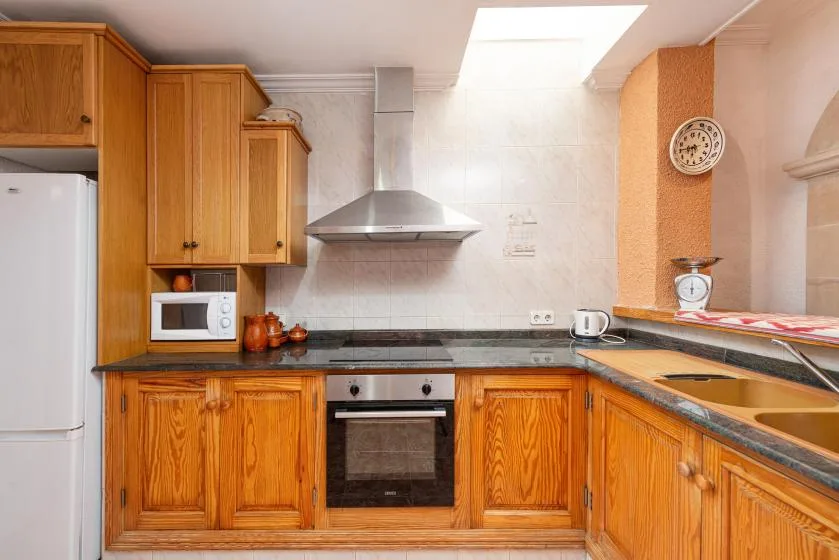 Una cocina con armarios de madera, un horno integrado y una encimera.