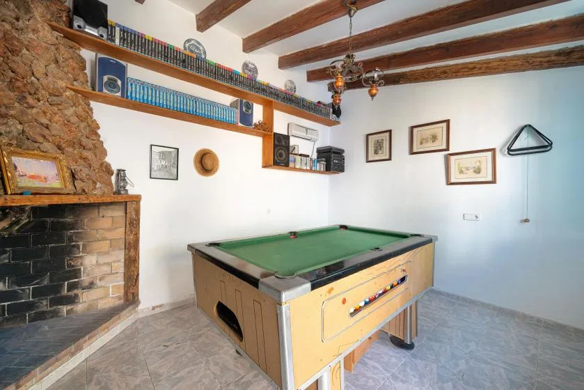 A game room with a pool table, wall shelves, and a stone fireplace.