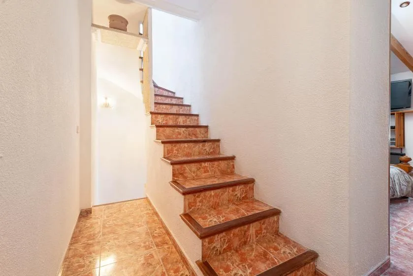 A tiled staircase rises beside a narrow tiled hallway.