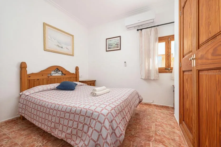 A bedroom with a wooden bed, patterned bedding, and a window.
