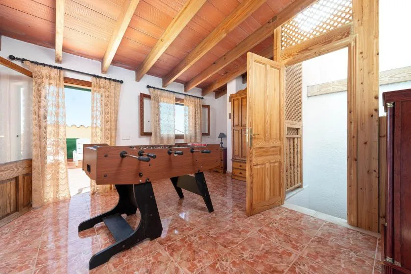 A game room with a foosball table beneath a wooden-beam ceiling.