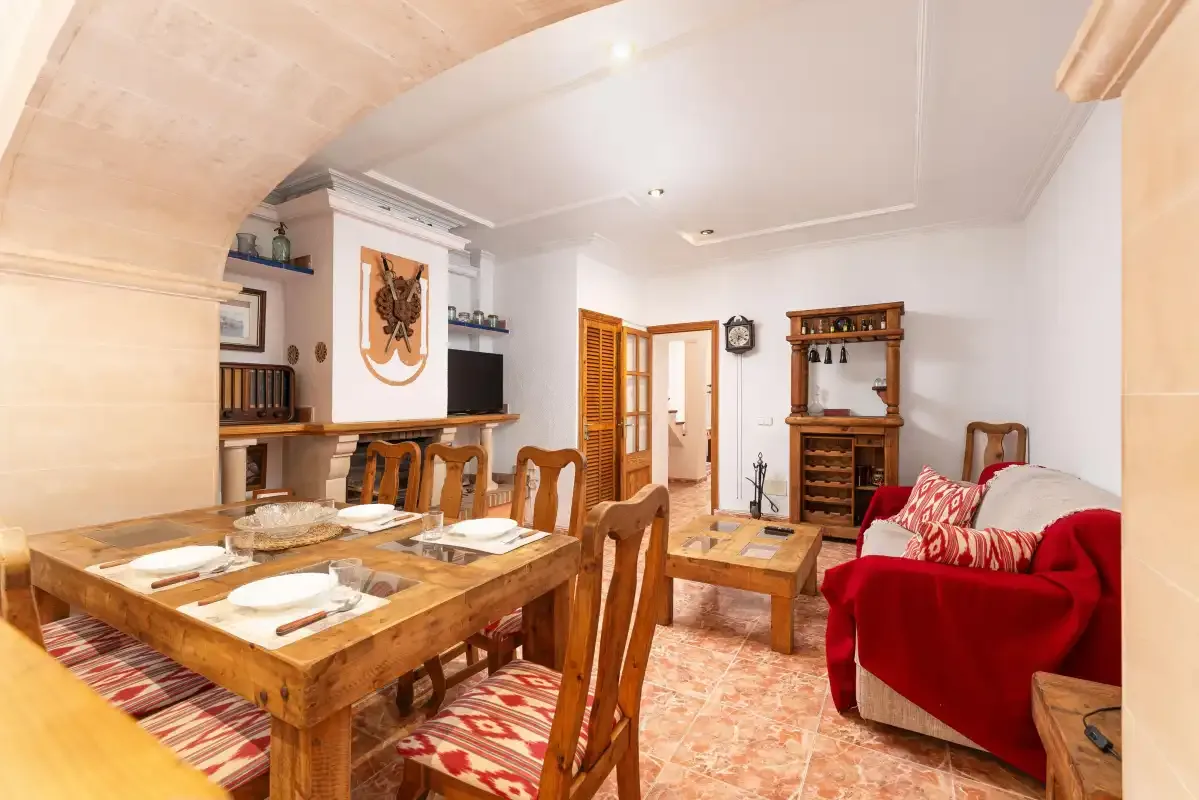 A dining and sitting room with a wooden table and red seating.