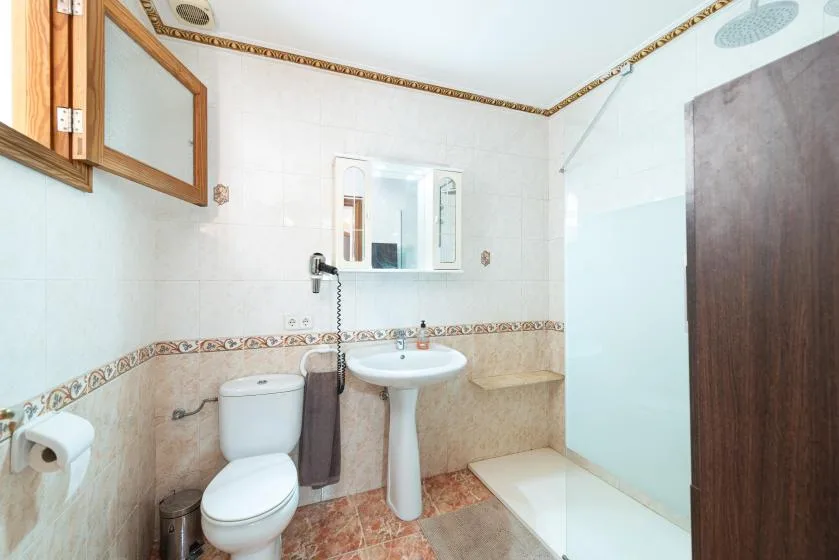 A tiled bathroom with a pedestal sink, toilet, and shower.