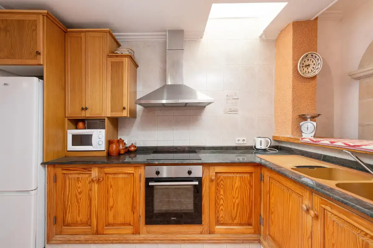 A kitchen with wooden cabinets, a countertop, and cooking appliances.